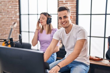 Erkek ve kadın müzisyenler müzik stüdyosunda beste yapıyorlar.