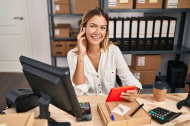 Latin kökenli genç bir kadın iş kadını dokunmatik ped kullanarak ofiste müzik dinliyor.