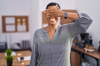 Ofiste çalışan Afro-Amerikalı kadın gözlük takıyor, gülümsüyor ve elleri yüzüne gülüyor şaşkınlıktan gözleri kapatıyordu. kör kavram. 