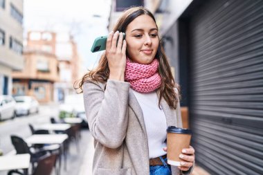 Genç, güzel, İspanyol bir kadın. Akıllı telefondan sesli mesaj dinliyor. Sokakta kahve içiyor.