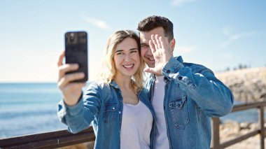 Erkek ve kadın bir arada, deniz kenarında görüntülü görüşme yapıyorlar.