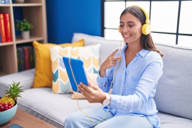 Genç İspanyol kadın tabletle video görüşmesi yapıyor. Kulaklık takıyor. Gülümsüyor. 