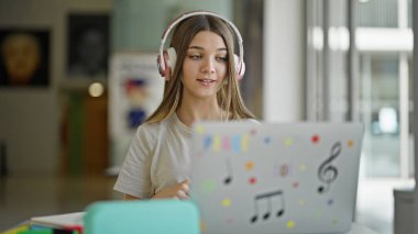 Genç ve güzel bir kız kütüphanede video görüşmesi yapıyor.