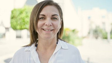 Middle age hispanic woman smiling confident at street