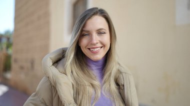 Sokakta kendine güvenen genç sarışın kadın gülümsüyor