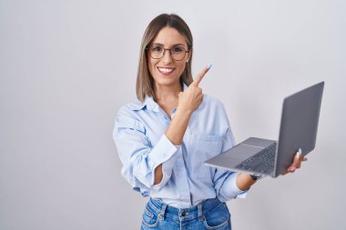 Bilgisayarda çalışan genç bir kadın, mutlu ve doğal ifadeyle elleri ve parmaklarıyla gülümseyen neşeli bir gülümseme ile mutlu bir dizüstü bilgisayar kullanıyor. 