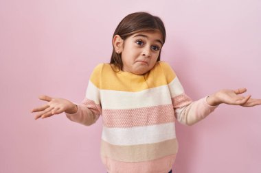 Küçük İspanyol kız pembe arka planda kazak giyip el ele tutuşarak bağırıyor ve bağırıyordu. iletişim konsepti. 