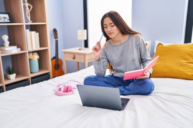 Genç, güzel İspanyol kız öğrenci. Yatak odasında şüpheyle ders çalışıyor.