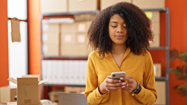 Ofisteki akıllı telefonu kullanan Afrikalı Amerikalı kadın ecommerce işçisi.