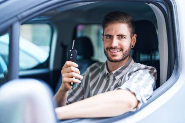 Young caucasian man smiling confident holding key of new car at street