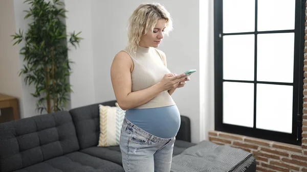 Mujer Embarazada Joven Usando Teléfono Inteligente Casa —  Fotos de Stock