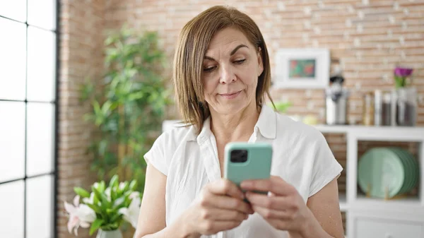 中年惊慌失措的女人在饭厅用智能手机 — 图库照片