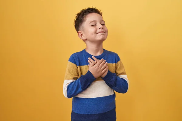 Sarı Arka Planda Duran Küçük Spanyol Çocuk Elleri Göğsünde Gözleri — Stok fotoğraf