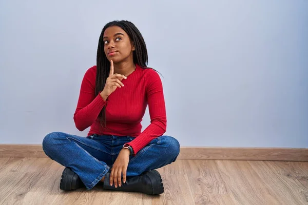 Joven Afroamericano Con Trenzas Sentado Suelo Casa Pensando Concentrado Duda —  Fotos de Stock