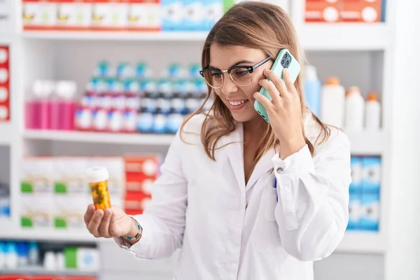 若い女性薬剤師保持薬瓶スマートフォンで話す薬局 — ストック写真