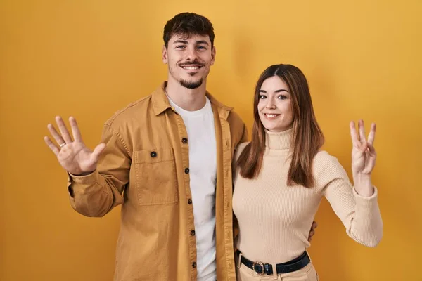 Young Hispanic Couple Standing Yellow Background Showing Pointing Fingers Number — Stock Photo, Image