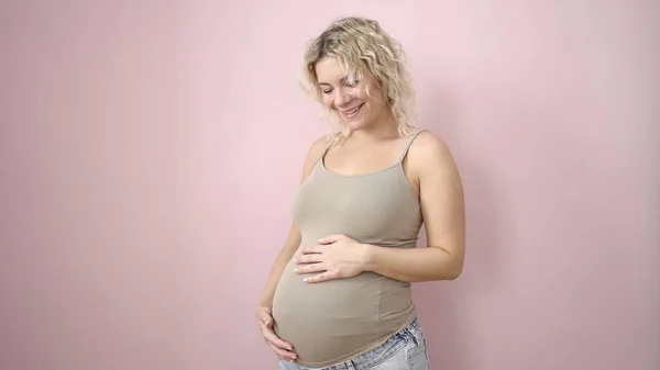 Joven Embarazada Sonriendo Confiado Tocando Vientre Sobre Aislado Rosa Fondo — Foto de Stock
