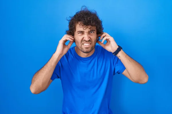 Hispanic Ung Man Står Över Blå Bakgrund Täcker Öron Med — Stockfoto