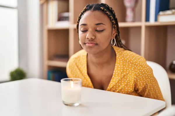 非洲裔美国妇女坐在桌子上 在家里闻芳香的蜡烛 — 图库照片