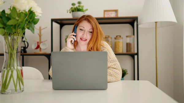 年轻的红头发女人在家里用笔记本电脑和智能手机聊天 — 图库照片