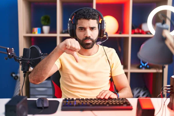 ヘッドフォンでビデオゲームをプレイする髭を持つヒスパニック系の男は 不満と怒りを示し拒絶と親指ダウンジェスチャーで陰性です 悪い表現 — ストック写真