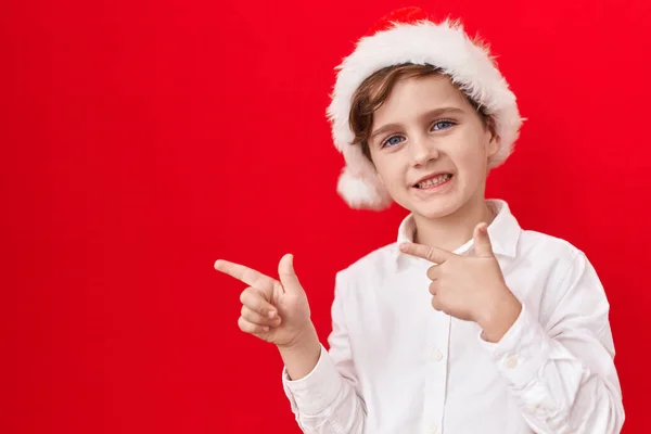 Malý Kavkazský Chlapec Nosí Vánoční Klobouk Červeném Pozadí Úsměvem Dívá — Stock fotografie