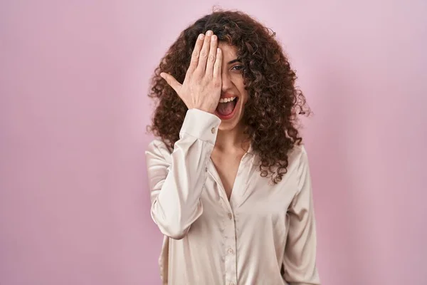 Hispanic Woman Curly Hair Standing Pink Background Covering One Eye — Zdjęcie stockowe