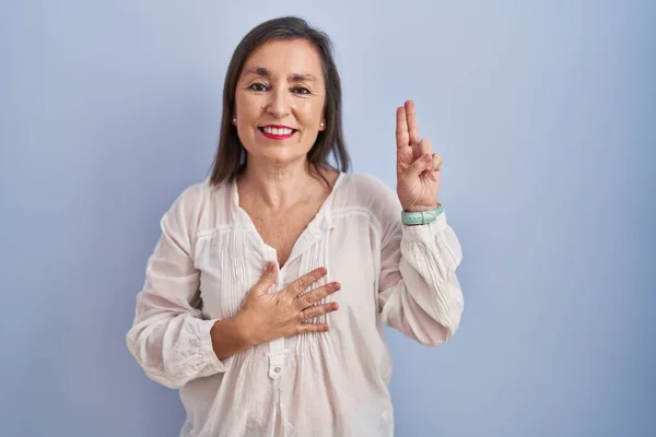 Mujer Hispana Mediana Edad Pie Sobre Fondo Azul Sonriendo Jurando —  Fotos de Stock