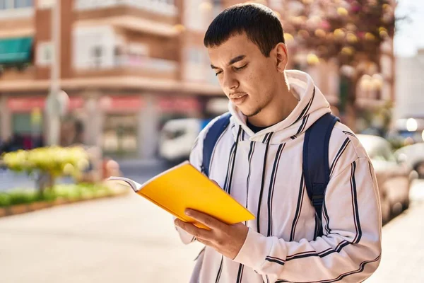 一个年轻的学生站在街上看书 — 图库照片