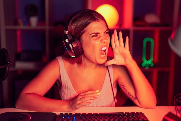 年轻的金发女人带着耳机玩电子游戏 一边大喊一边大叫 传播概念 — 图库照片