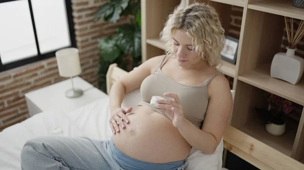 若いです妊娠中の女性適用皮膚ローション上腹にベッドルーム — ストック写真