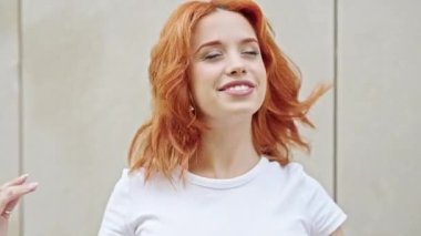 Genç, kızıl saçlı, kendine güvenen, saçlarını tarayan, izole beyaz arka planı olan bir kadın.