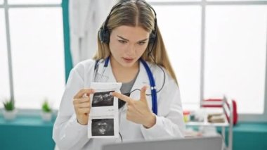 Klinikteki bebek ultrasonunu gösteren video görüntülü sarışın kadın doktor.