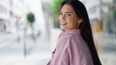 Genç, güzel, İspanyol bir kadın gülümsüyor kendine güveni tam, saçlarını tarıyor.