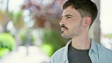 Parkta kendinden emin gülümseyen İspanyol genç adam.