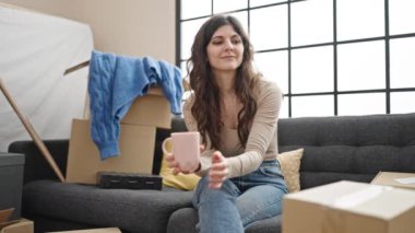 Genç, güzel, İspanyol bir kadın. Yeni evindeki kanepede kahve içiyor.