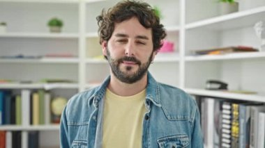 Young hispanic man student smiling confident standing at library university