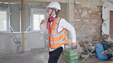 Kafkasyalı genç mimar inşaat alanında dans ederken gülümsüyor.