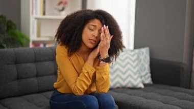 Afrikalı Amerikalı kadın evdeki kanepede otururken strese girdi.