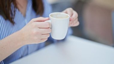 Kahve dükkanının terasında kahve içen genç, güzel İspanyol kadın.
