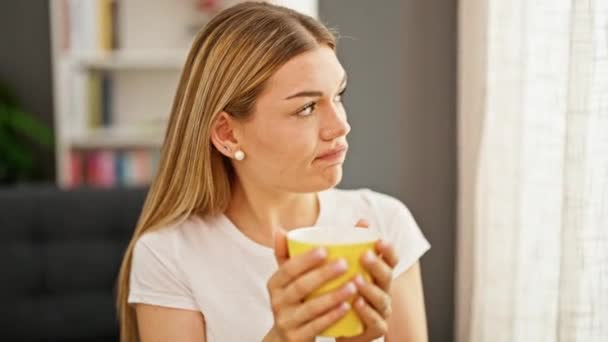Junge Blonde Frau Trinkt Hause Kaffee Mit Traurigem Gesichtsausdruck — Stockvideo