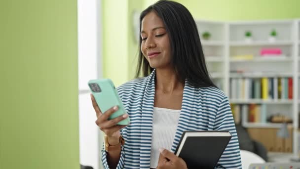 Africano Americano Mulher Estudante Usando Smartphone Segurando Livro Universidade Biblioteca — Vídeo de Stock