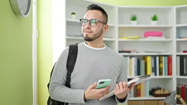 Estudiante Hispano Sonriendo Confiado Usando Smartphone Universidad Biblioteca — Vídeo de stock