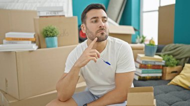 Kanepede oturan genç İspanyol adam yeni evini düşünüyor.