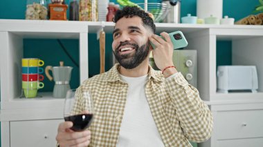 Genç İspanyol adam bir bardak şarap içiyor. Yemek odasında akıllı telefondan sesli mesaj dinliyor.