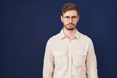 Mavi arka planda sakallı İspanyol bir adam depresyonda ve üzüntüden ağlıyor, kızgın ve korkmuş. hüzünlü ifade. 