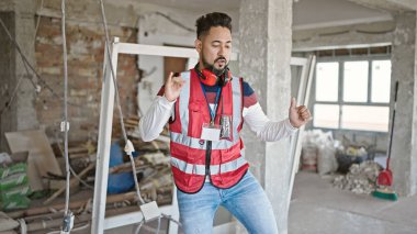 Şantiyede dans ederken gülümseyen genç latin mimar.