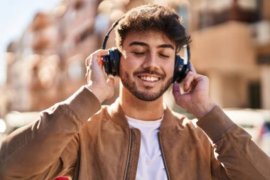 Sokakta müzik dinlerken kendinden emin gülümseyen İspanyol genç adam.