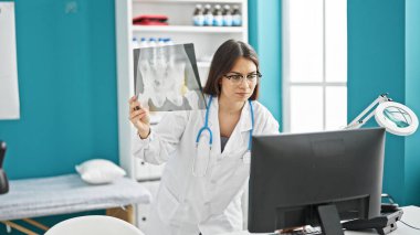 Genç, güzel İspanyol kadın doktor Xray 'e bakıyor. Klinikte bilgisayarla duruyor.