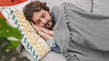Genç İspanyol adam kanepede uzanıp evde uyuyor.